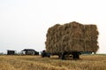 Low-angle view of a walk-behind tractor carrying piles of straw bales Royalty Free Stock Photo