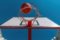 Low angle view of ball falling through hoops at outdoor basketball court Royalty Free Stock Photo