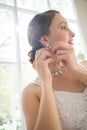 Low angle view of beautiful bride wearing earring while standing by window Royalty Free Stock Photo