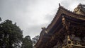 Low angle view of beautiful wooden with gold roof of japanese temple with top of big trees on cloudy sky background Royalty Free Stock Photo