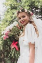 low angle view of beautiful young bride holding wedding bouquet and smiling Royalty Free Stock Photo