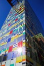 Low angle view beyond colorful skyscraper facade with windows against dark blue clear cloudless sky, sunburst effect