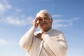 Low angle view of biracial senior woman shielding eyes while looking away against sky on sunny day