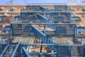Low angle view of blue fire escape stairs mounted to the outside of the brick building`s wall, used for emergency exit Royalty Free Stock Photo