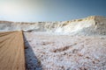 Low angle view of brine salt farm with blue sky. Pile of organic sea salt near warehouse. Raw material of salt industrial. Ocean