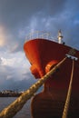 Low angle view of cargo ship docked at port against rain cloudy sky at sunset time Royalty Free Stock Photo