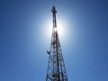 Cellular or mobile network tower against the sun in the blue sky. Royalty Free Stock Photo