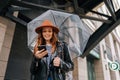 Low-angle view of cheerful elegant young woman wearing fashion hat using typing mobile phone smiling looking to screen Royalty Free Stock Photo