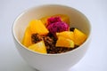 Low angle view close up of breakfast - muesli with fruits orange and dragon fruit in white ceramic bowl, on white background. Royalty Free Stock Photo