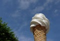 Low angle view, close up a cold soft cream in waffle cone on summer , blurry background of blue bright sky,