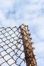 Low angle view close-up of wire wood fence against light blue sky, abstract of chain link fence on cloud backdrop