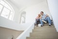 Low angle view of couple with painting tools sitting on steps in new house