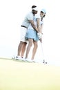 Low angle view of couple playing golf at course against clear sky