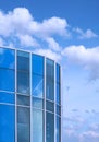 Curved glass office building against white clouds on blue sky background Royalty Free Stock Photo