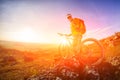 Low angle view of cyclist standing with mountain bike on trail at sunset Royalty Free Stock Photo