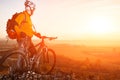 Low angle view of cyclist standing with mountain bike on trail at sunset Royalty Free Stock Photo