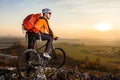 Low angle view of cyclist standing with mountain bike on trail at sunset Royalty Free Stock Photo