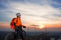 Low angle view of cyclist standing with mountain bike on trail at sunset Royalty Free Stock Photo