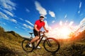 Low angle view of cyclist standing with mountain bike on trail at sunset Royalty Free Stock Photo