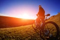 Low angle view of cyclist standing with mountain bike on trail at sunset Royalty Free Stock Photo