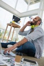 Low angle view of designer talking on mobile phone while sitting on floor Royalty Free Stock Photo