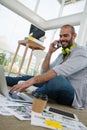 Low angle view of designer talking on mobile phone while using laptop Royalty Free Stock Photo