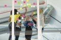Business people giving high five while discussing over sticky notes on glass wall in a modern office