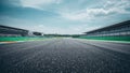 Low angle view down an empty asphalt racetrack showing grandstands on both sides beneath a bright blue sky with scattered white Royalty Free Stock Photo