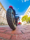 Low angle view of e-scooter tire with city buildings and trees Royalty Free Stock Photo