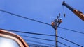 2 electricians with crane truck are working to install electrical system on electric power pole against blue sky Royalty Free Stock Photo