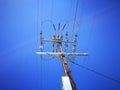 A Low angle view of Electricity High Voltage Transformer for Sending Power Line Energy Generation isolated on blue sky background.