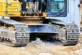 Low-angle view of an excavator\'s crawler tracks and base section at a construction site. Royalty Free Stock Photo