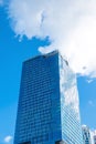 Low angle view exterior of high modern tower building office structure with glass window reflection and blue sky white clouds