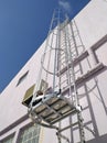 Low angle view of an exterior vertical fixed ladder with safety cage in a building. White facade under blue sky. Building Royalty Free Stock Photo