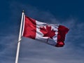 Low angle view of flying Canadian national flag with white and red colors and maple leaf in center on flagpole. Royalty Free Stock Photo