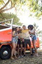 Low angle view of friends looking at map at campsite