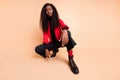 Low angle view full body photo of afro american stunning lady sit wear boots red blazer isolated on beige color