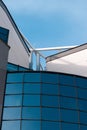 A low angle view of a glass building and a roof with pipes smoking up the air during a sunny day