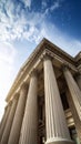 Low-angle view of a grand building with Corinthian columns against a blue cloudy sky. Royalty Free Stock Photo