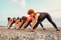 Low angle view of group of Caucasian women wearing sportswear stretching on beach. Copy space. Concept of outdoor sport