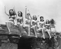Low angle view of a group of women sitting on a stone structure and waving their hands Royalty Free Stock Photo