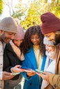 Group of young multi-ethnic friends using cell phones outdoors. People addicted to technology. Royalty Free Stock Photo