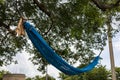 Blue netting nylon hammock tied to a large tree branch.