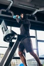 low angle view of handsome sportsman in hoodie exercising on treadmill and drinking water Royalty Free Stock Photo