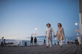 Low angle view of happy senior couple walking outdoors on pier by sea at dusk, holding hands. Royalty Free Stock Photo