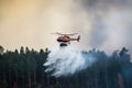 Helicopter putting out fire over tall trees