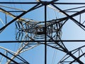 Low angle view of a high electricity pillar   from inside against blue sky Royalty Free Stock Photo