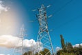 Low angle view of high voltage towers and electric cables against sunny blue sky Royalty Free Stock Photo