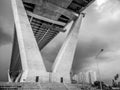 Low angle view of huge and stately bridge with cloudy sky and tower in the background, urban and futuristic concept Royalty Free Stock Photo