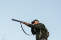 Hunter aiming with his gun with sky in background Royalty Free Stock Photo